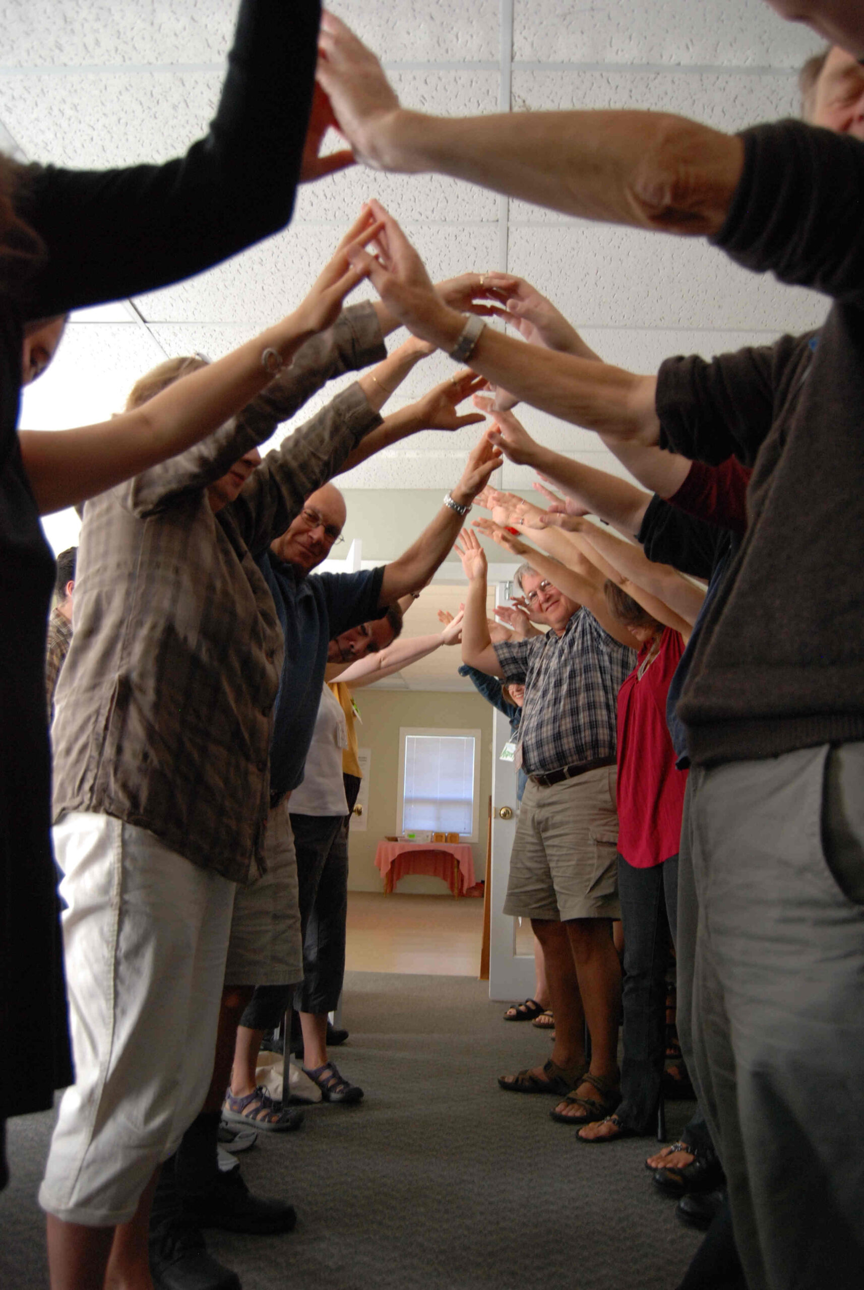 adults holding their hands together high in the air, making an arch