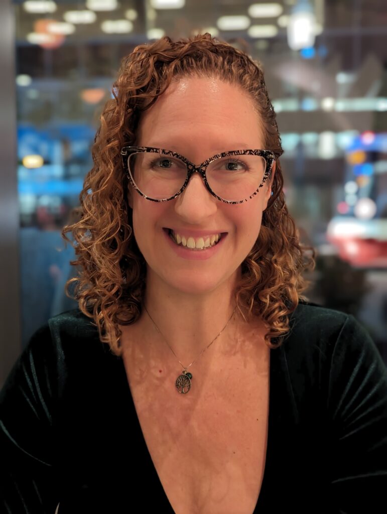 Smiling woman with dark blond curly hair wearing glasses